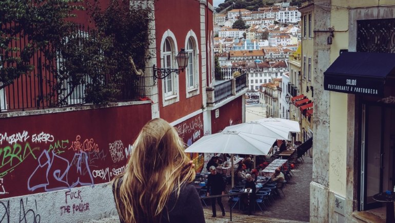 A stylish young traveler exploring a narrow cobblestone street in one of Europe's coolest cities, with historic buildings and vibrant street art in the background, representing a unique European adventure.