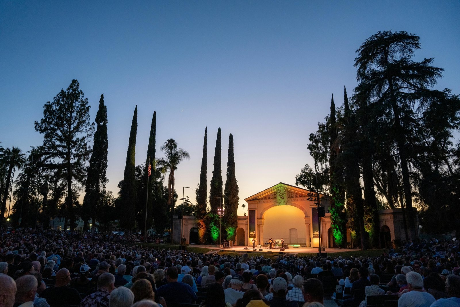 A multi-generational audience enjoying a classic rock festival in the California desert, evoking the legendary Desert Trip 'Oldchella' concert experience.