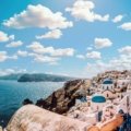 A stunning view of the iconic whitewashed village of Oia in Santorini, one of the best places to visit in Greece, with its blue-domed churches overlooking the Aegean Sea.