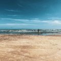 A wide, sandy Texas beach on a sunny day with gentle waves from the Gulf of Mexico, an ideal vacation spot.