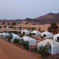 Luxury glamping tent in the rocky Agafay Desert at sunset, perfect for Marrakech desert tours and camel rides.