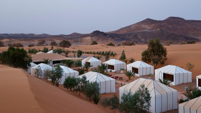 Luxury glamping tent in the rocky Agafay Desert at sunset, perfect for Marrakech desert tours and camel rides.