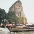 A stunning view of traditional longtail boats in a turquoise bay, an iconic destination for travelers deciding where to go in Thailand for beautiful beaches and adventure.