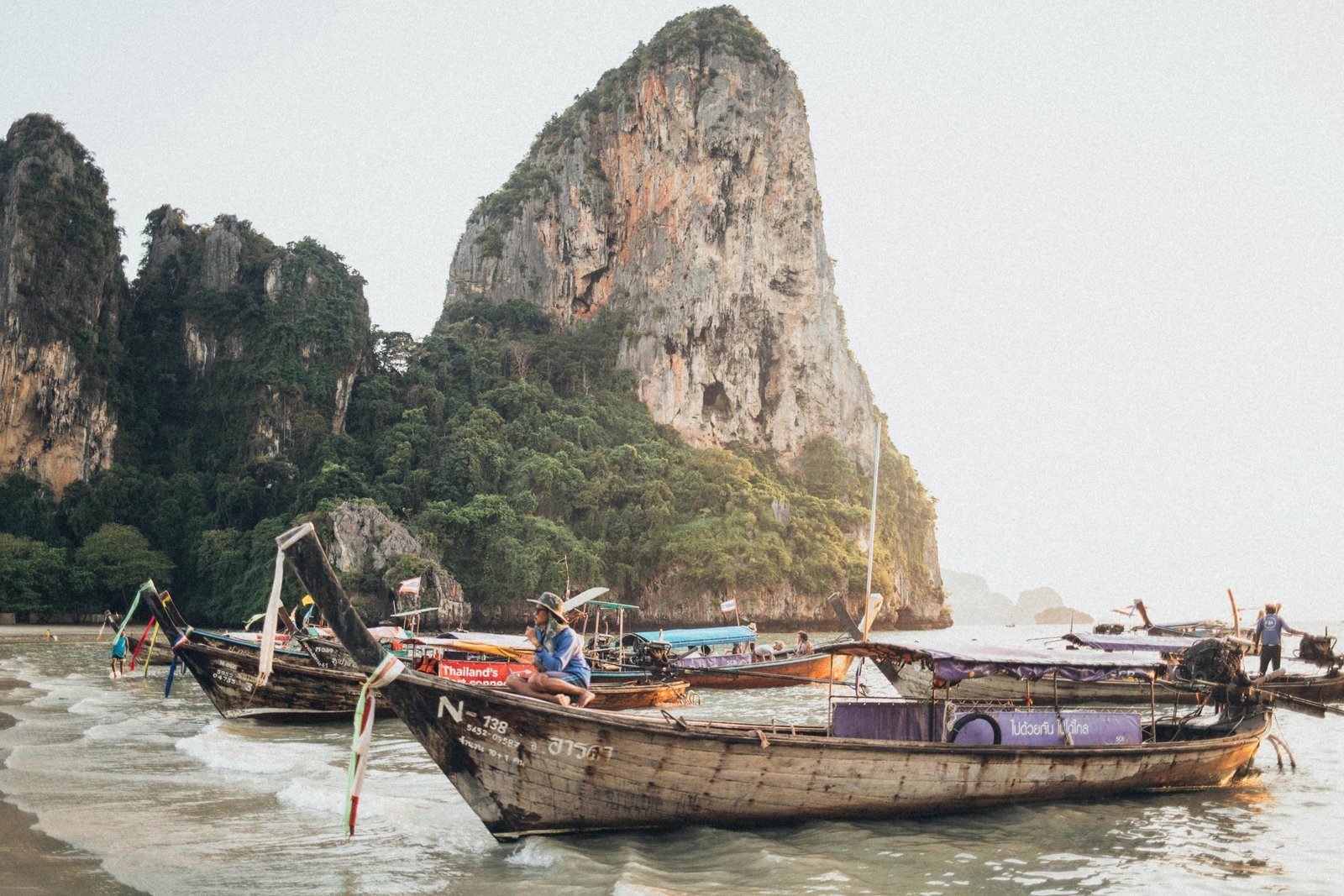 A stunning view of traditional longtail boats in a turquoise bay, an iconic destination for travelers deciding where to go in Thailand for beautiful beaches and adventure.