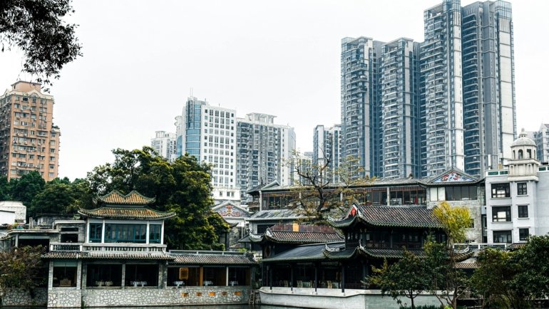 An ancient Chinese temple pagoda overlooks a modern city skyline at dusk, symbolizing the blend of history and innovation for a complete China travel adventure.