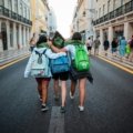 Young backpacker happily exploring a cobblestone street in a historic city, an example of an authentic and affordable low cost getaway.
