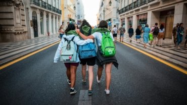 Young backpacker happily exploring a cobblestone street in a historic city, an example of an authentic and affordable low cost getaway.