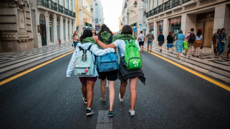 Young backpacker happily exploring a cobblestone street in a historic city, an example of an authentic and affordable low cost getaway.