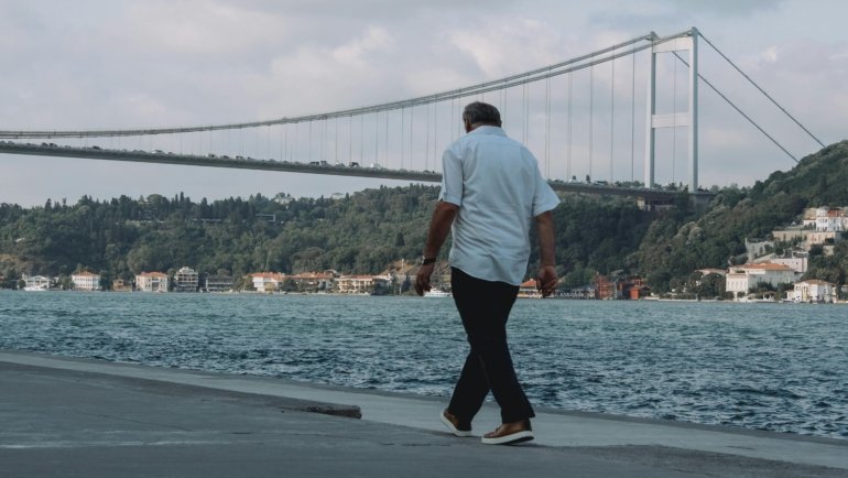 Man in versatile men's travel pants exploring a mixed urban and natural landscape, highlighting comfort, durability, and style for adventure travel and city exploration.