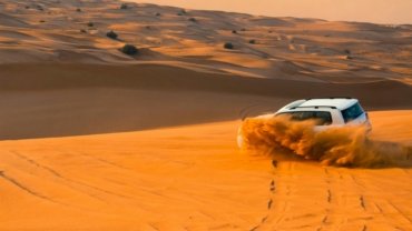 Thrilling Dubai desert safari adventure featuring a 4x4 vehicle navigating golden sand dunes at sunset, showcasing the iconic dune bashing experience and the majestic beauty of the Arabian desert for an unforgettable cultural tour.