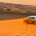 Evening desert safari Dubai experience with a camel ride on golden dunes at sunset, highlighting the adventure and cultural immersion.