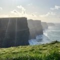 A stunning, wide-angle view of the iconic Cliffs of Moher, a key destination for planning a first trip to Ireland.