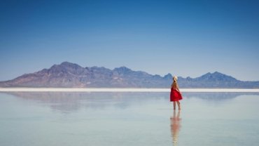 A solo female traveler stands on a viewpoint looking out over a scenic American mountain range, illustrating a safe and empowering trip to one of the best places to travel solo female in the US.