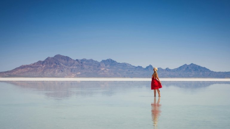 A solo female traveler stands on a viewpoint looking out over a scenic American mountain range, illustrating a safe and empowering trip to one of the best places to travel solo female in the US.