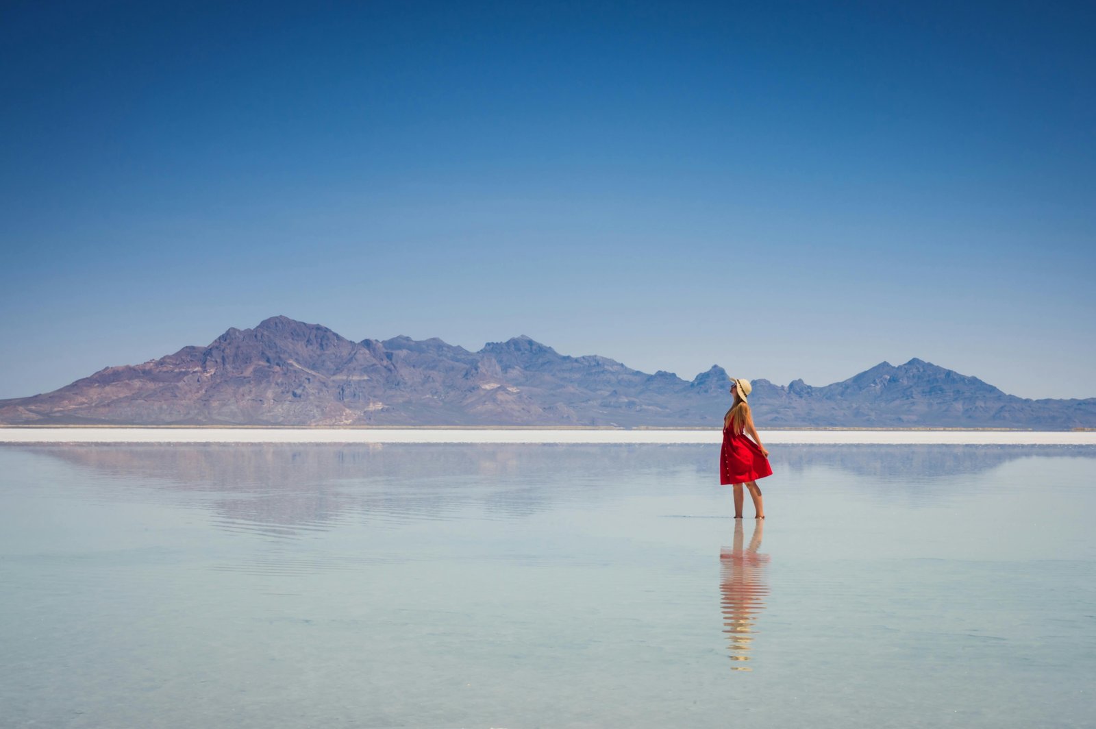 A solo female traveler stands on a viewpoint looking out over a scenic American mountain range, illustrating a safe and empowering trip to one of the best places to travel solo female in the US.