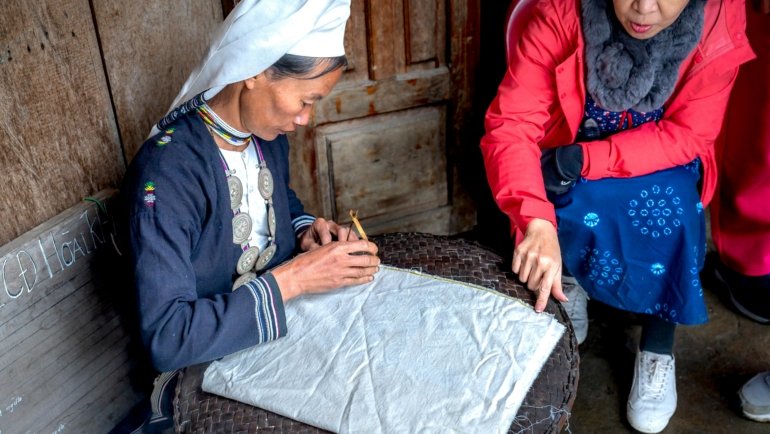 A traveler learning a traditional craft from a local artisan, an example of an authentic and unique cultural immersion experience.