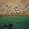 An aerial view of one of the best beaches in NJ, showcasing the beautiful coastline with golden sand and blue ocean waves under a bright summer sun.