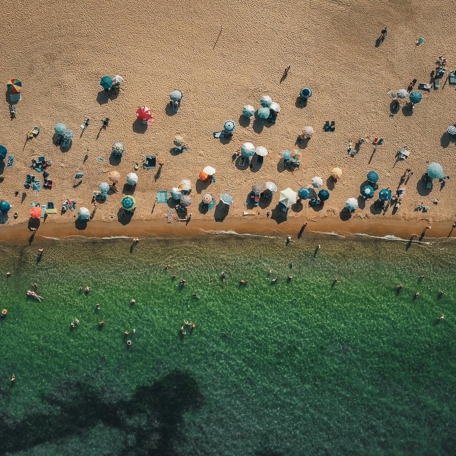 An aerial view of one of the best beaches in NJ, showcasing the beautiful coastline with golden sand and blue ocean waves under a bright summer sun.