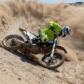 Desert Gateway Dirt Bike Tours: An exhilarating off-road adventure with a rider on a dirt bike, speeding through vast desert dunes and canyons, wearing full safety gear.