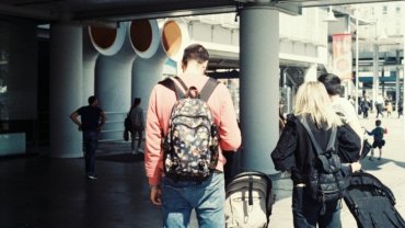 Happy backpacker exploring a vibrant budget-friendly city street, symbolizing affordable travel and smart backpacking tips.