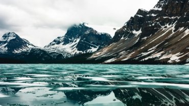 Majestic landscape of Glacier National Park with towering mountains and a serene lake, featuring hikers enjoying a stress-free, guided tour, symbolizing the benefits of a travel agency.
