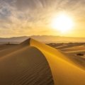 Vibrant desert sunrise over endless sand dunes, showcasing the serene beauty of a desert awakenings tour.