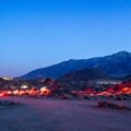 A traditional Sahara desert camp in Morocco at night, with glowing tents and a campfire under a brilliant starry sky over the dunes.