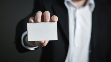 A professional individual holding a UofL travel card, symbolizing efficient university business travel expense management for faculty and staff.
