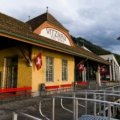 Panoramic view of a scenic Swiss travel package destination, featuring majestic Alps, a tranquil lake, a charming village, and an iconic train, highlighting diverse and convenient exploration.