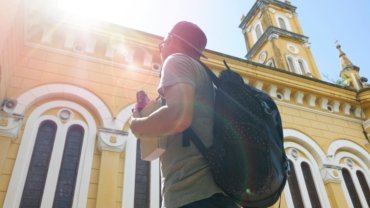 A traveler with a backpack overlooks a historic cityscape, representing one of the best places to travel cheap in Europe.