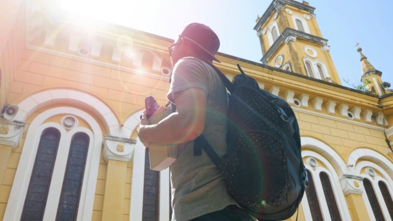 A traveler with a backpack overlooks a historic cityscape, representing one of the best places to travel cheap in Europe.