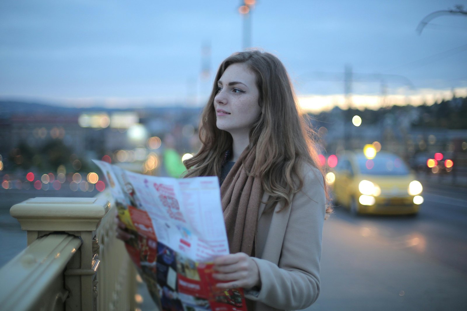A young person happily plans their route with a map for a budget-friendly road trip to cheap travel spots in the US.