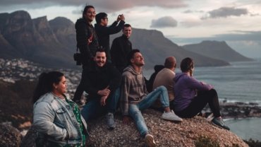 A group of happy friends on a holidays for singles over 40 Australia tour, laughing together with a beautiful coastal landscape in the background.