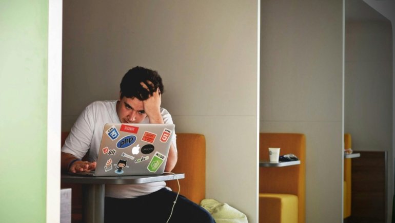 A stressed person looking at a non-functional computer, representing the start of a Tripp Lite insurance claim process for equipment damaged by a power surge.