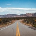A scenic view of a car on an open road heading towards mountains, illustrating the adventure of finding the best places to travel in the US.
