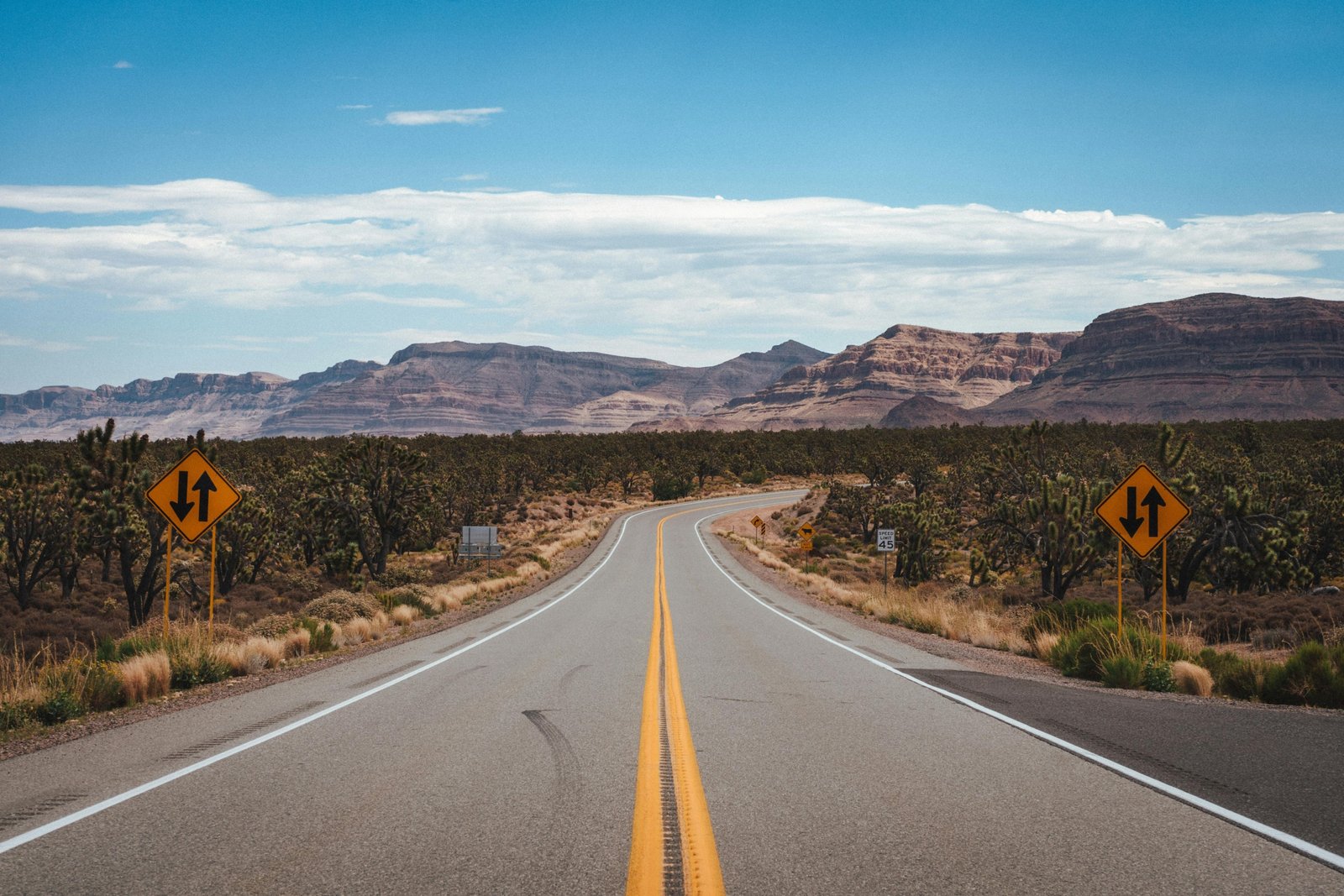 A scenic view of a car on an open road heading towards mountains, illustrating the adventure of finding the best places to travel in the US.