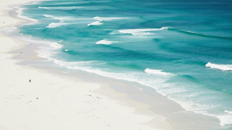 Aerial view of the pristine white sand beaches and clear turquoise water of South Padre Island, Texas, on a sunny day.