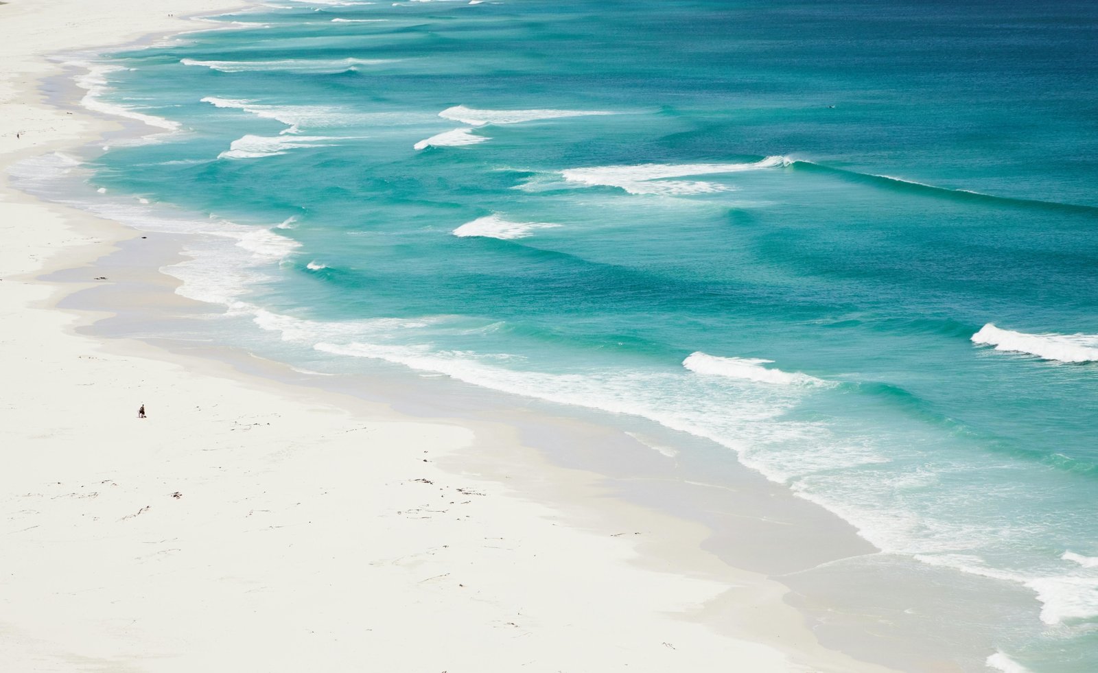Aerial view of the pristine white sand beaches and clear turquoise water of South Padre Island, Texas, on a sunny day.