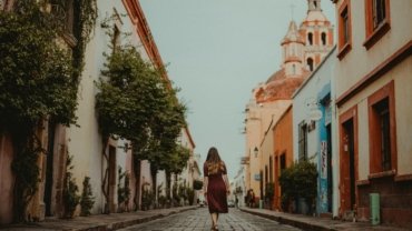 Solo traveler with a small backpack exploring a picturesque cobblestone street in a historic European city, representing freedom and safety for independent adventures.