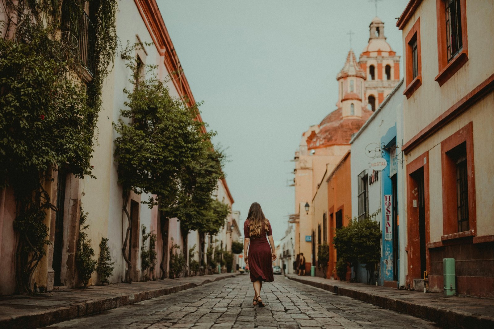 Solo traveler with a small backpack exploring a picturesque cobblestone street in a historic European city, representing freedom and safety for independent adventures.