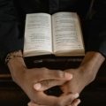 Christian prayer for safe travels, featuring hands clasped in prayer with a travel-related background, symbolizing divine protection and peace for journeys.
