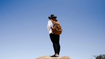 Happy traveler with a durable and comfortable rucksack in a beautiful landscape, illustrating the best gear for hassle-free adventure travel and long journeys.