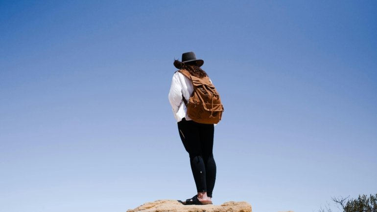 Happy traveler with a durable and comfortable rucksack in a beautiful landscape, illustrating the best gear for hassle-free adventure travel and long journeys.