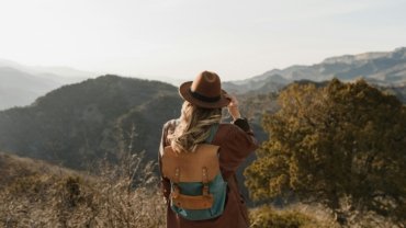 Traveler with a comfortable, carry-on compliant travel backpack exploring a vibrant city street or scenic outdoor trail, ideal for various adventures.