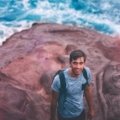 A young traveler with a backpack looks out over a scenic landscape, representing the joy of discovering cheap places to see and traveling on a budget.