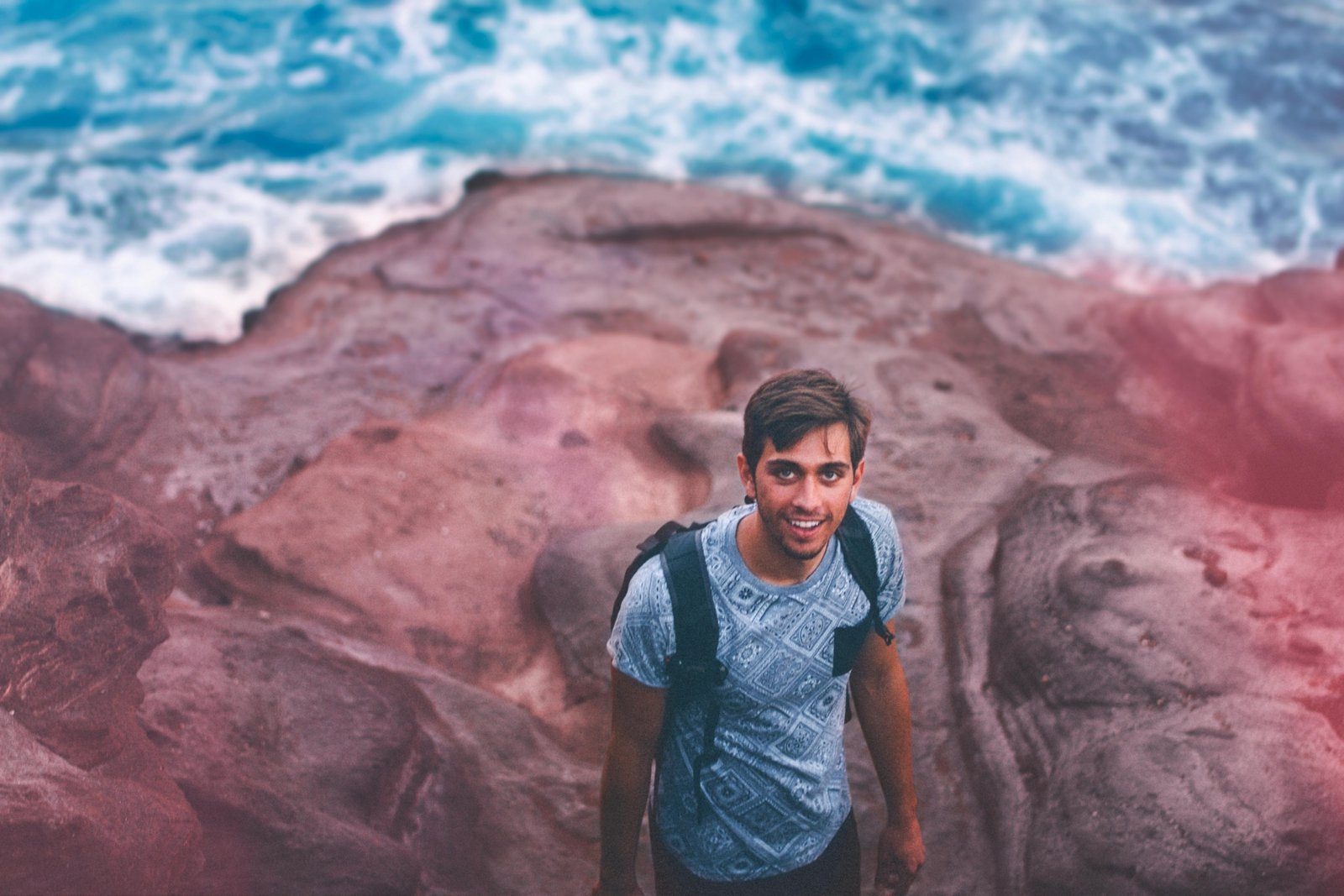 A young traveler with a backpack looks out over a scenic landscape, representing the joy of discovering cheap places to see and traveling on a budget.
