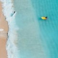 Sunny aerial view of the New Jersey coastline, showing a beautiful sandy beach and the Atlantic Ocean, a perfect spot to find a beach in NJ for a summer vacation.