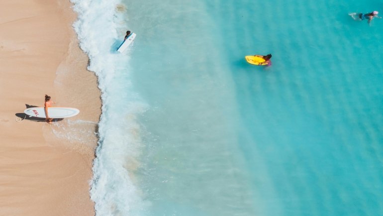 Sunny aerial view of the New Jersey coastline, showing a beautiful sandy beach and the Atlantic Ocean, a perfect spot to find a beach in NJ for a summer vacation.