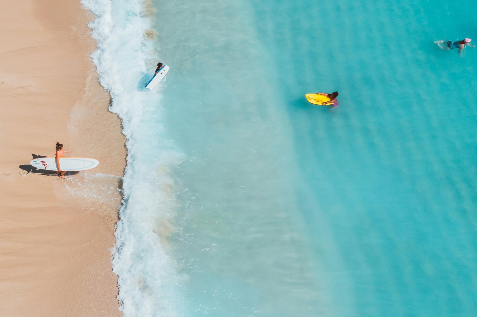 Sunny aerial view of the New Jersey coastline, showing a beautiful sandy beach and the Atlantic Ocean, a perfect spot to find a beach in NJ for a summer vacation.