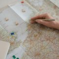Person meticulously planning a detailed travel itinerary for a successful Schengen visa application to Europe, with a map, passport, and booking documents on a table.